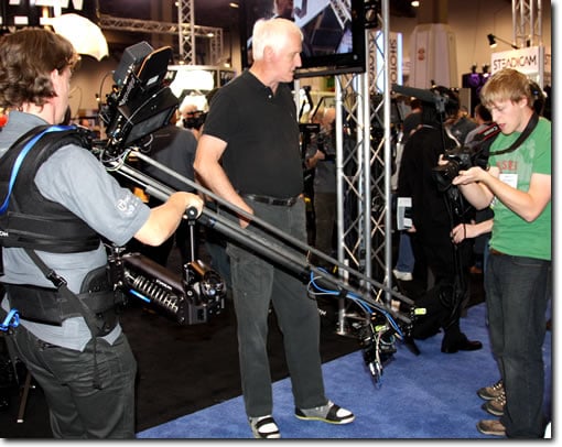 Garrett Brown (center) gives a Steadicam demonstration at the Tiffen Booth for StudentFilmmakers Magazine. Jon Firestone (not in frame) and Tim Hardy (far right) capture the demo using a Canon 7D DSLR